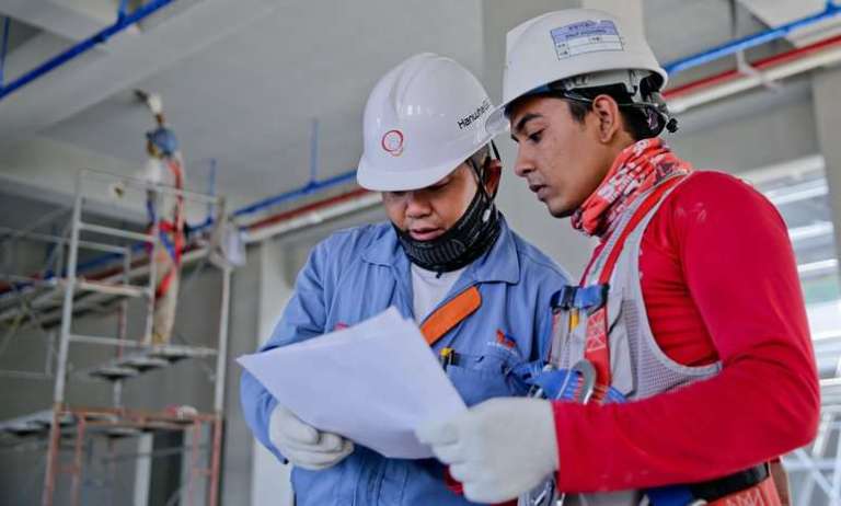 Construction workers reviewing embodied carbon and energy efficiency metrics of sustainability on site.