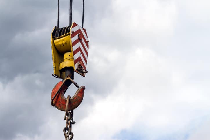 Colorful crane hook adhering to ASME B30.23-2022 personnel lifting systems requirements basking in the sky.