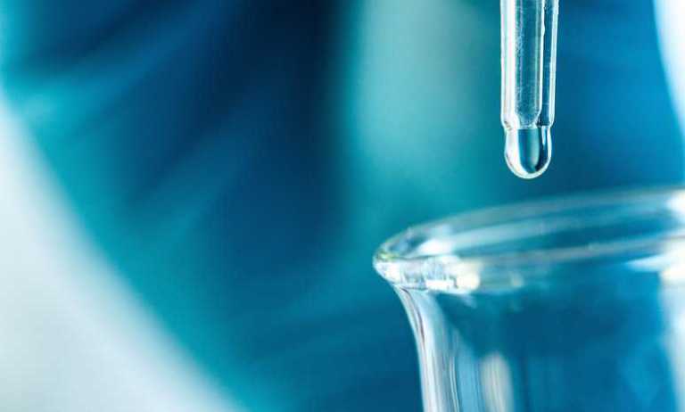 Quality chemical dropping from pipette into beaker showing the benefits of laboratory accreditation.