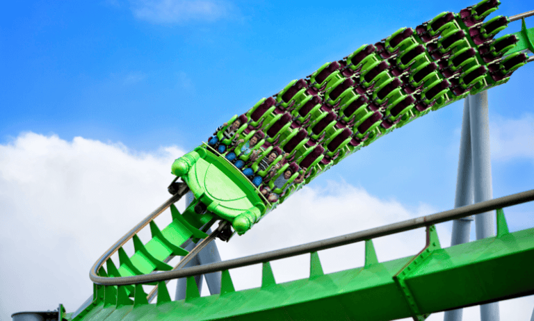 Roller coaster twisting patrons in green cars in the sky that was designed by following ASTM F2291-23.