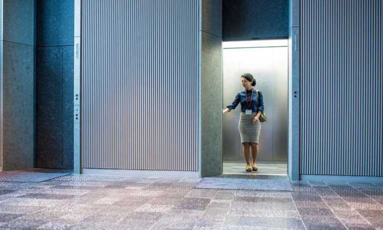 Woman getting in elevator adhering to ASME A17.1 and benefitting from a long history.