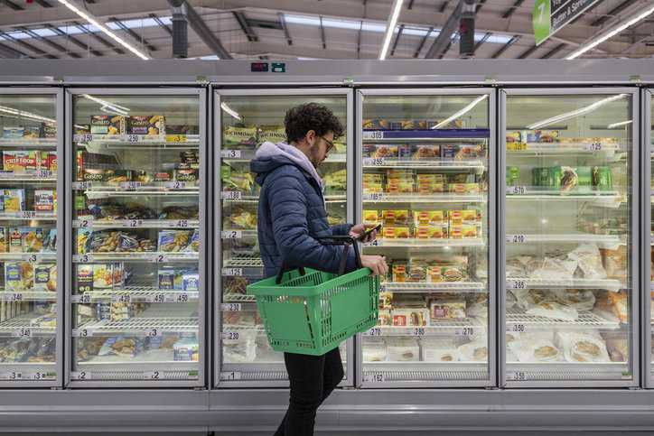 Man grocery shopping in a market with commercial refrigerators adhering to ANSI/ASHRAE 72-2022.