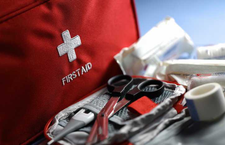 A red workplace first aid kit filled with the proper ANSI Z308.1-2021 standard contents.