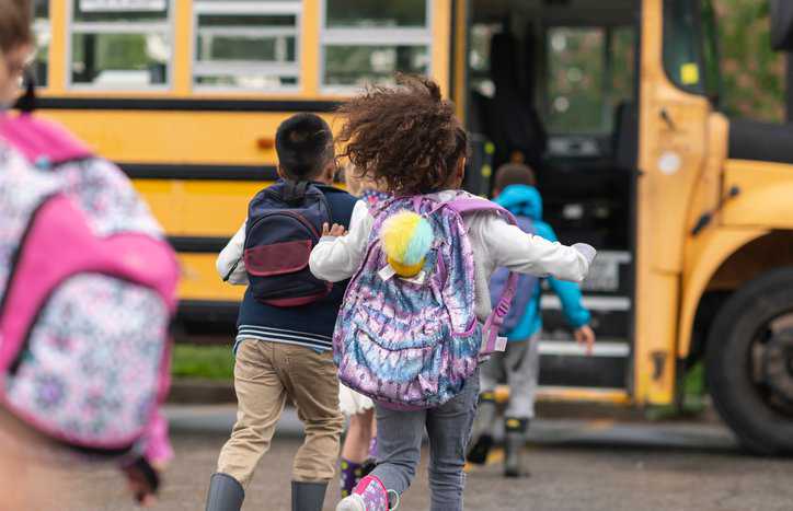 Happy children boarding a CSA D250-2022 school bus.