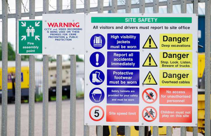 Construction site with sign posting colorful safety symbols adhering to ANSI Z535.3-2022 criteria.