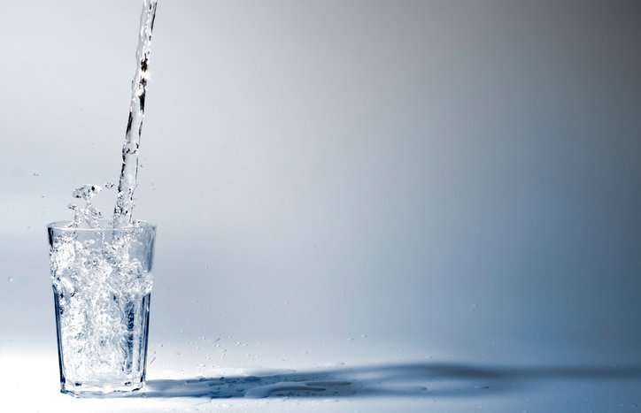 Glass of water being filled with water that follows ANSI 61-2022.