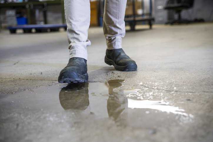 Worker about to slip on wet floor and hence management not adhering to ANSI/ASSP A1264.2-2022: Reducing Slip Missteps.