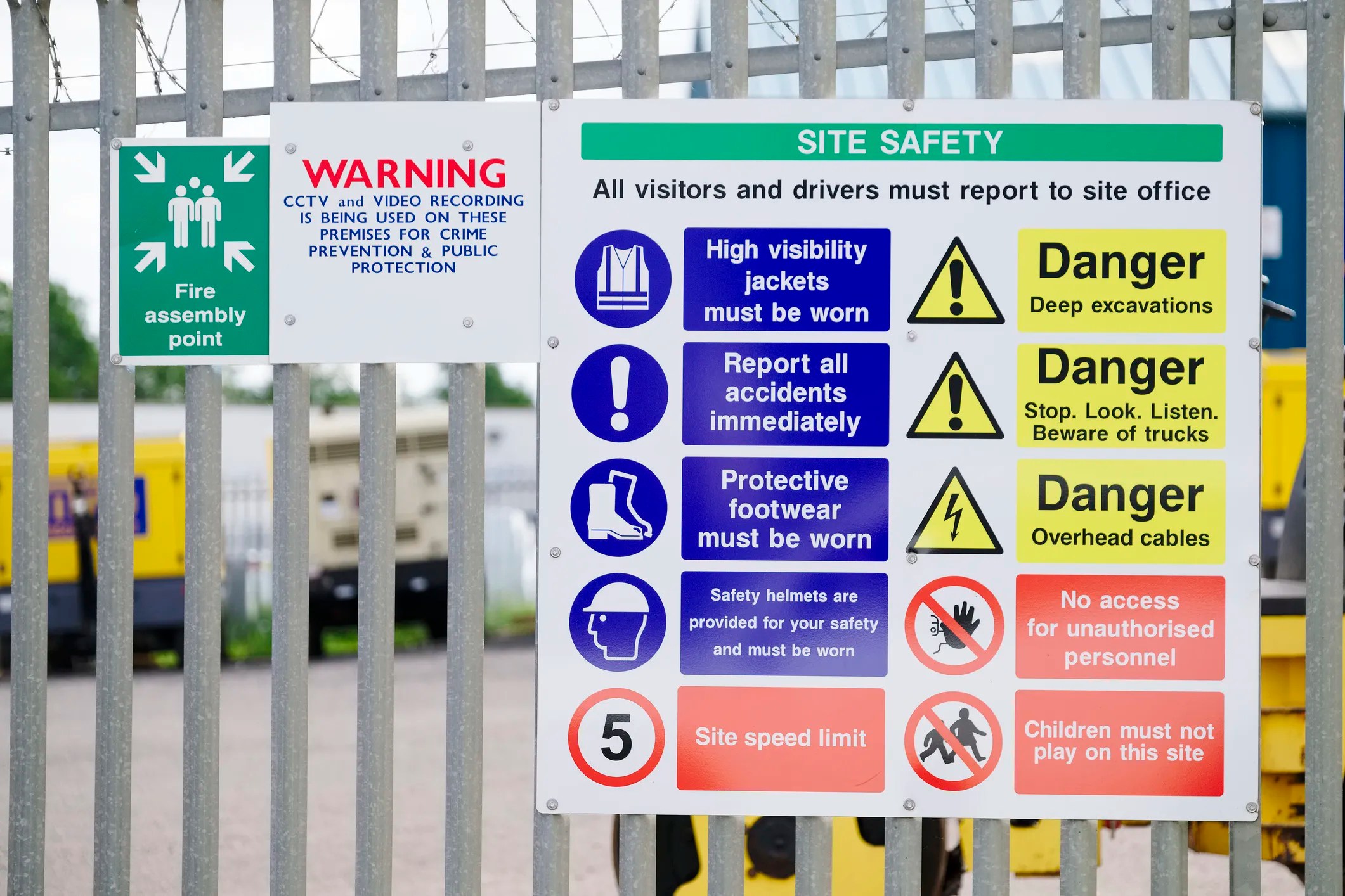 Construction site with sign posting colorful safety symbols adhering to ANSI Z535.3-2022 criteria.