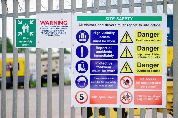 Construction site with sign posting colorful safety symbols adhering to ANSI Z535.3-2022 criteria.