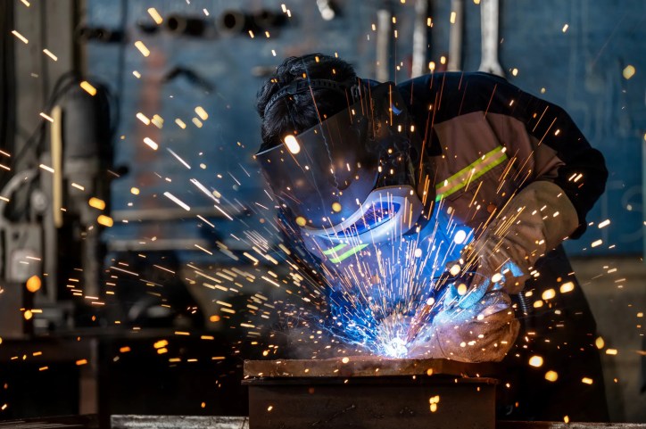 Welder Wearing Safety and Health Equipment Adhering to ANSI Z49.1-2021.