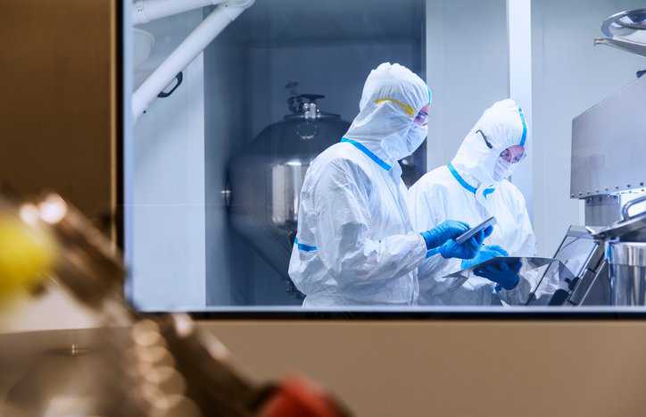Lab technicians in PPE working and trusted due to accreditation.