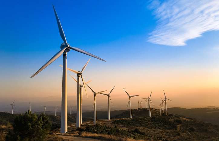 Wind turbines in line under sky and assured to the power performance measurements of IEC 61400-12-1 Ed. 3.0 B:2022.