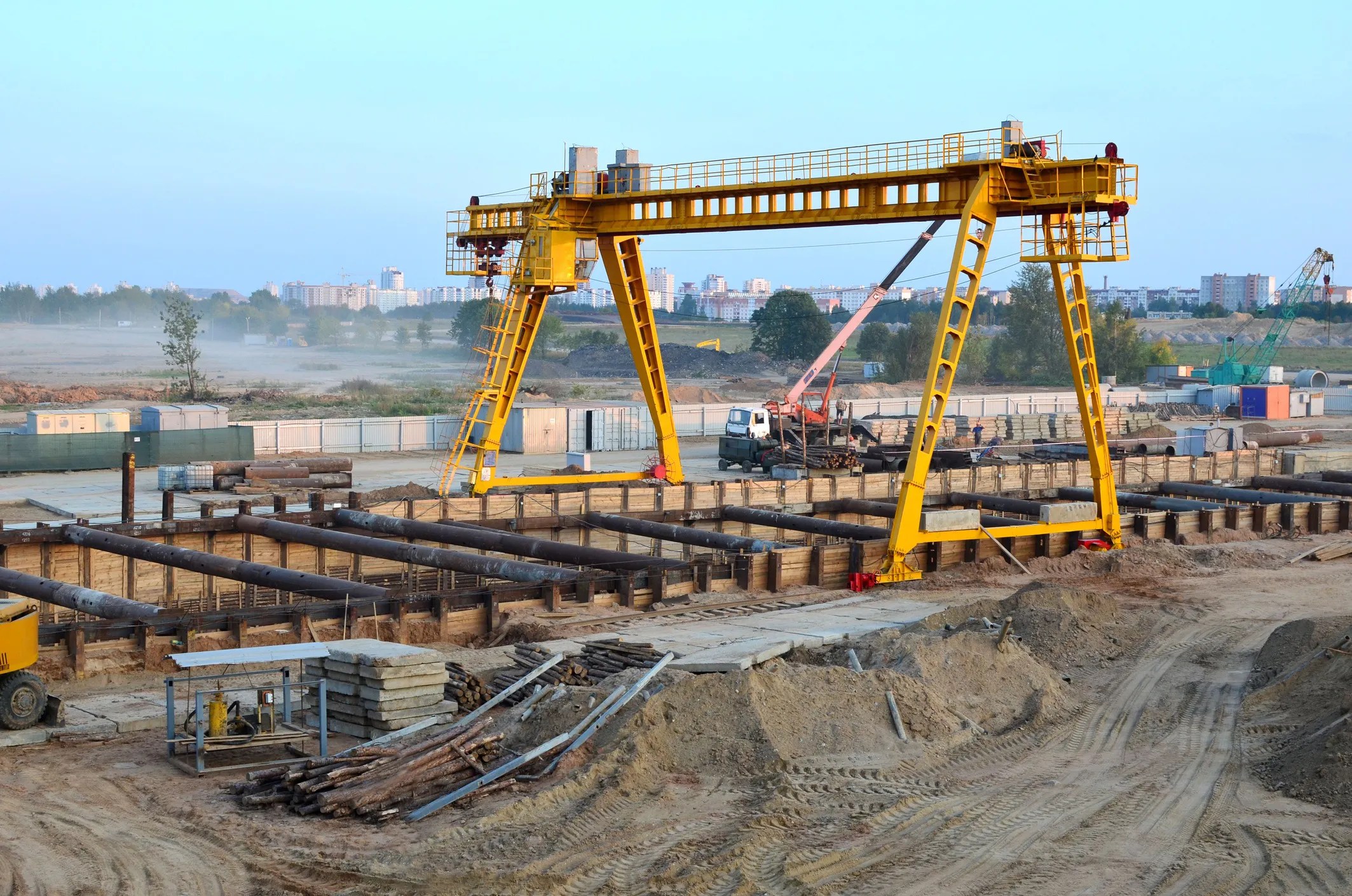 An overhead gantry crane operating at an outdoor construction site that is lifting a heavy load; the crane is adhering to ASME B30.2‑2022 standard's safety requirements.