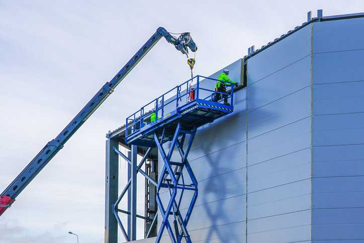 Scissor lift at construction site adhering to safety requirements specified in ANSI MH29.1-2020.
