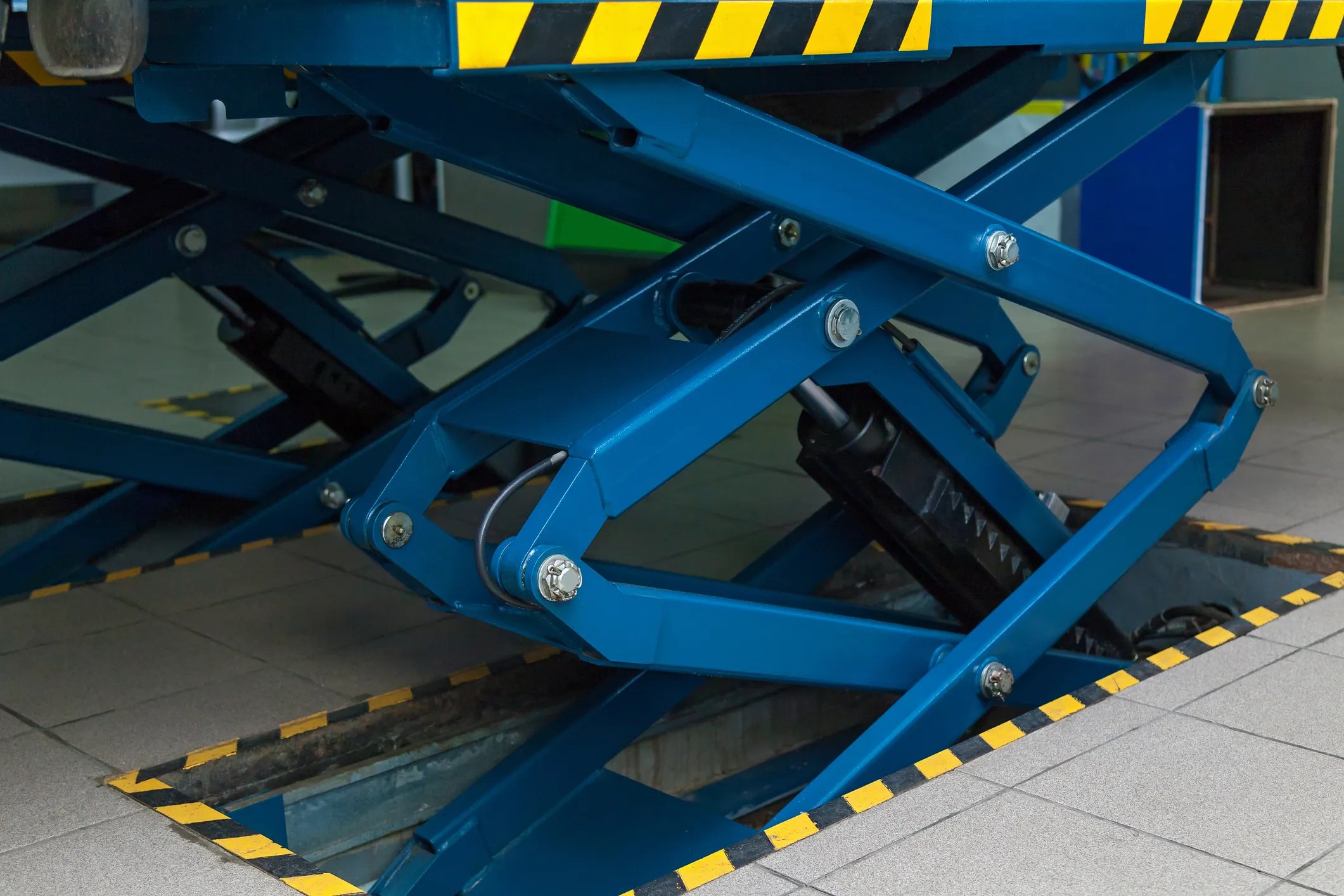 Closeup of a blue scissors lift table covered by ANSI MH29.1.
