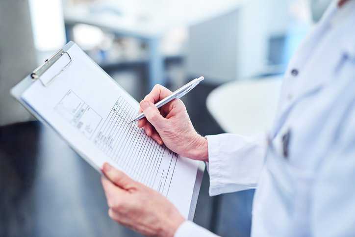 Laboratory worker filling out an IEC test report form (TRF), adhering to electrical safety.