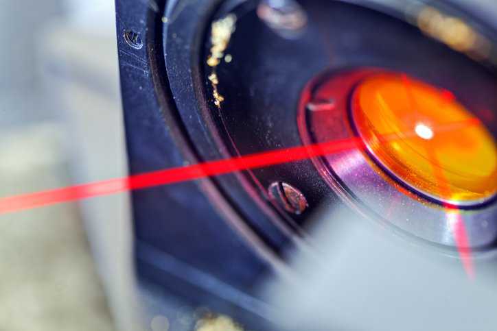 Red laser on optical table in physics laboratory, adhering to ANSI Z136.4-2021.
