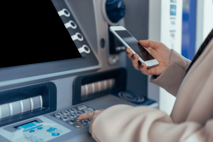 Woman making a banking transaction at an ATM that adheres to cryptography checklist in ISO 13491-2:2023.