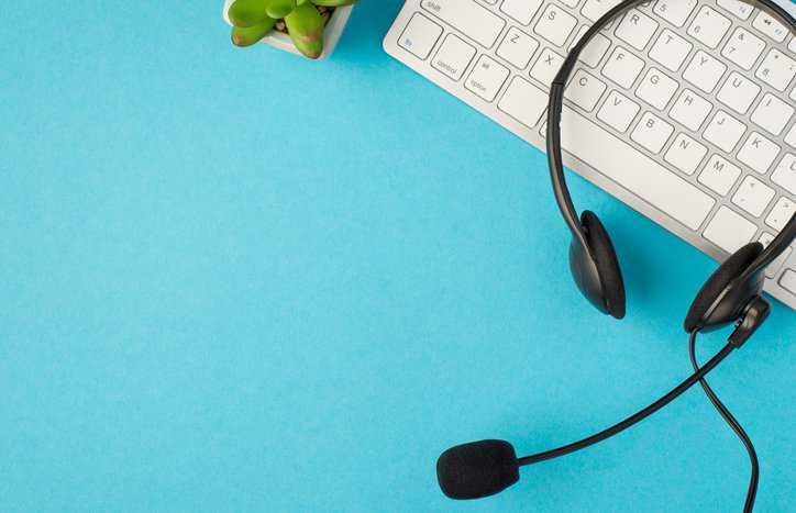 Customer service headset and keyboard over blue counter.