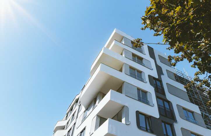Futuristic white building beside tree in Germany adhering to ANSI/ASHRAE 90.1-2022 requirements.