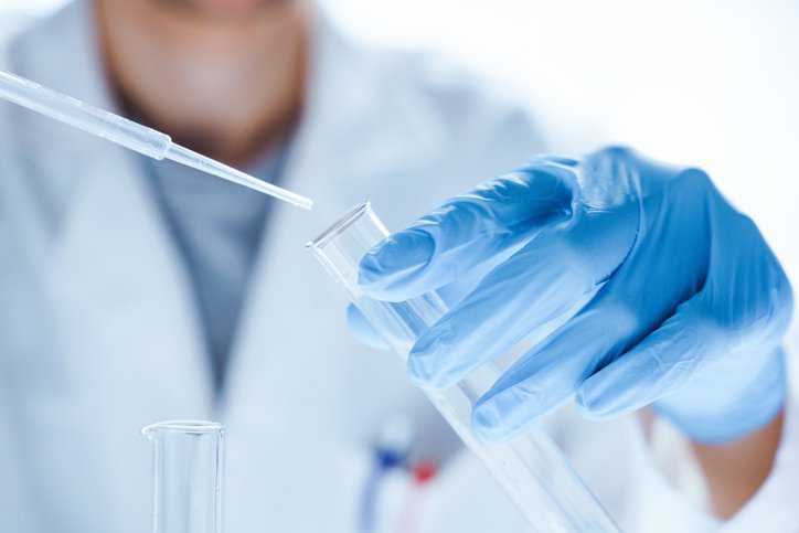 Researcher using a test tube to perform interference testing in clinical chemistry lab, adhering to CLSI EP07-Ed3 (R2022).