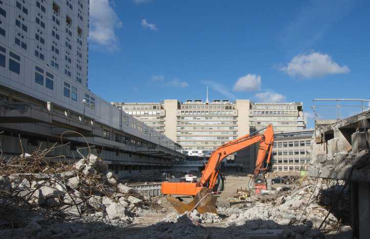 Hospital being demolished by ANAB accredited certificate holding construction professional in orange crane.