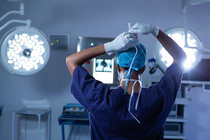 Health care professional wearing protective surgical drapes that adheres to ANSI/AAMI PB70:202.