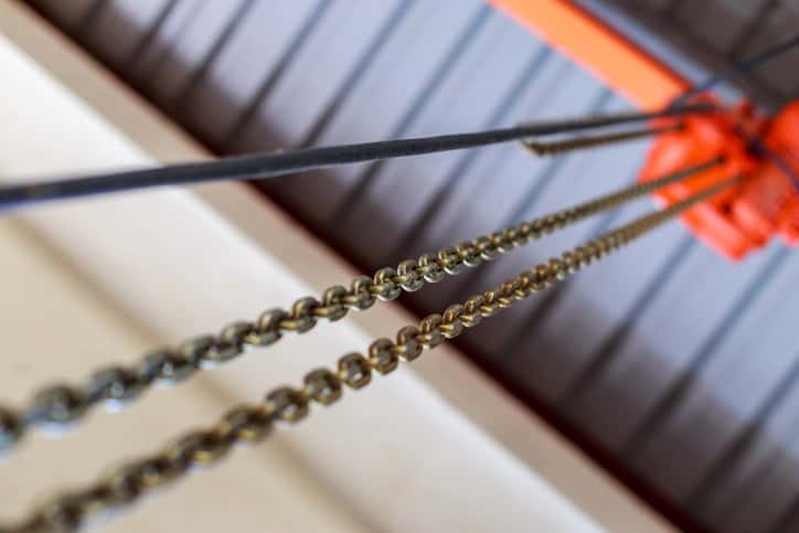 Chrome chains lowering from orange ASME HST-3-2022 lever hoist.
