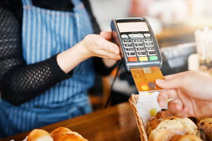 Customer making a credit card purchase at a retail store with the card reader adhering to ANSI X9.104-1-2004 (R2023).