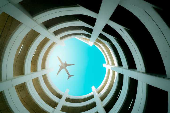 An airplane souring above open building due to AQMS certification quality and reliability.
