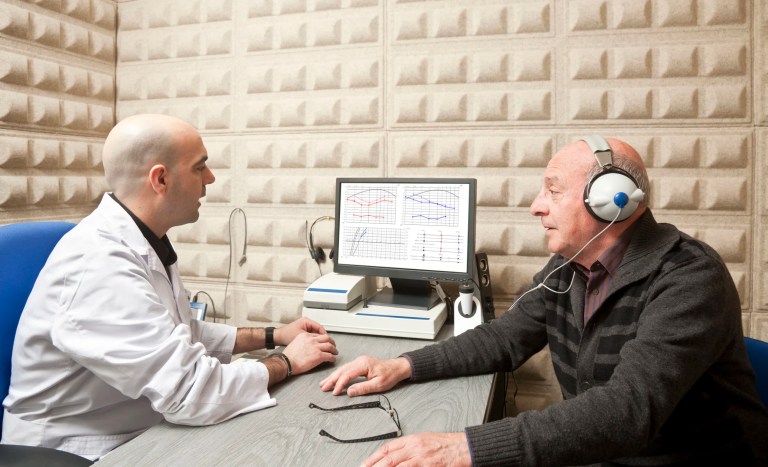 Patient getting pure tone hearing test at audiology center with an audiometer adhering to specifications in ASA/ANSI S3.6-2018 (R2023).