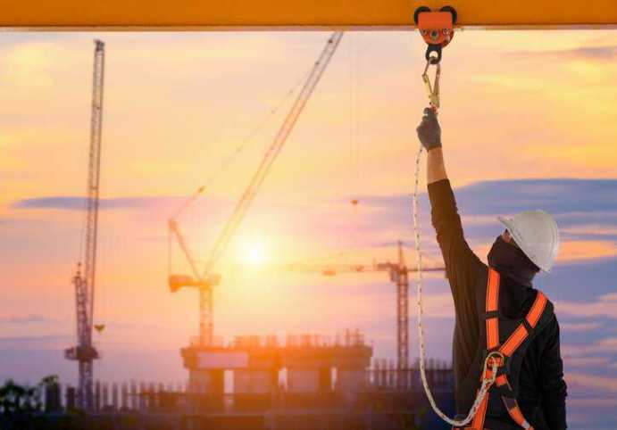 Construction worker adhering to ANSI/ASSP A10.32-2023 fall protection and fall prevention requirements.