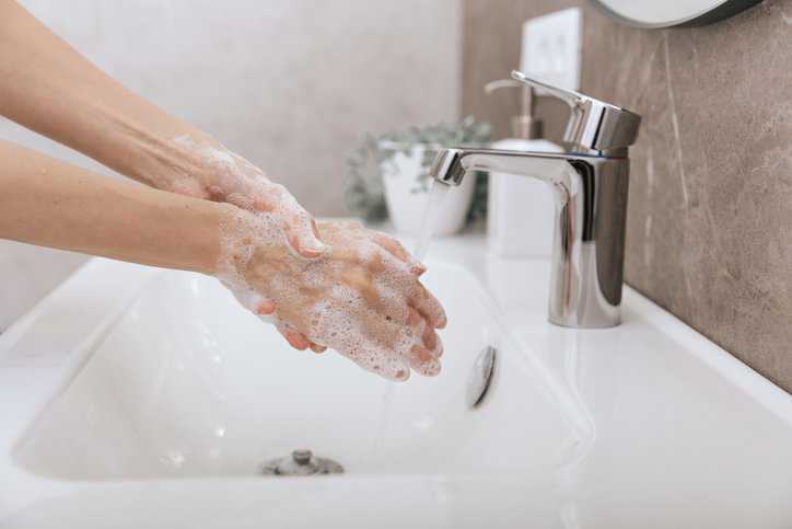 Human washing hands with soap for virus protection adhering to the test method in ASTM E2011-21.