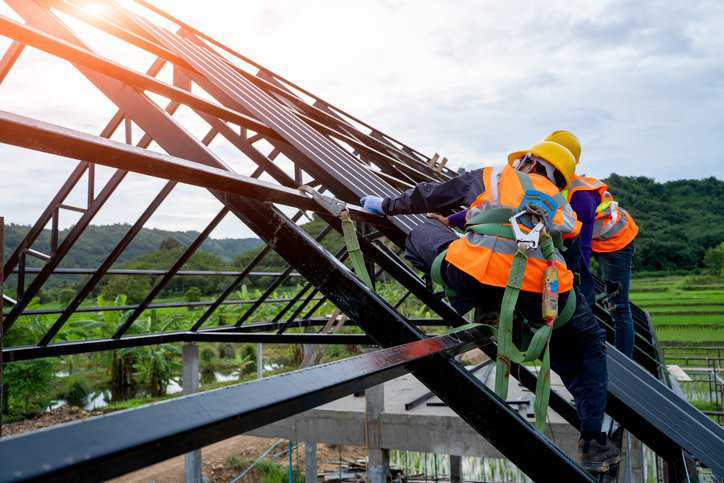 Construction worker wearing safety harness adhering to ANSI/ASSP Z359.2-2023 fall protection program.