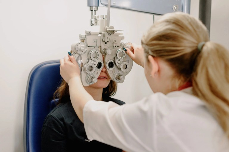 Woman getting eyes checked with optical devices for low vision that adhere to ANSI Z80.9-2020.