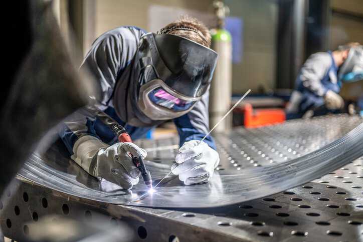 Welder adhering to ISO 13920:2023 general tolerance requirements.