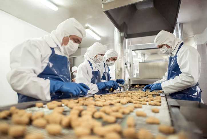 People working at a food factory assembly line with FSSC 24000 certification.