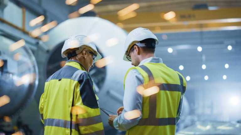 Engineers working in manufacturing plant with sparks flying.