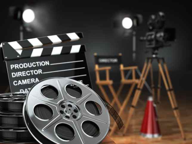 Retro camera, film reels (that adhere to ISO 4241:2019), clapperboard and director chair demonstrating cinema concept.