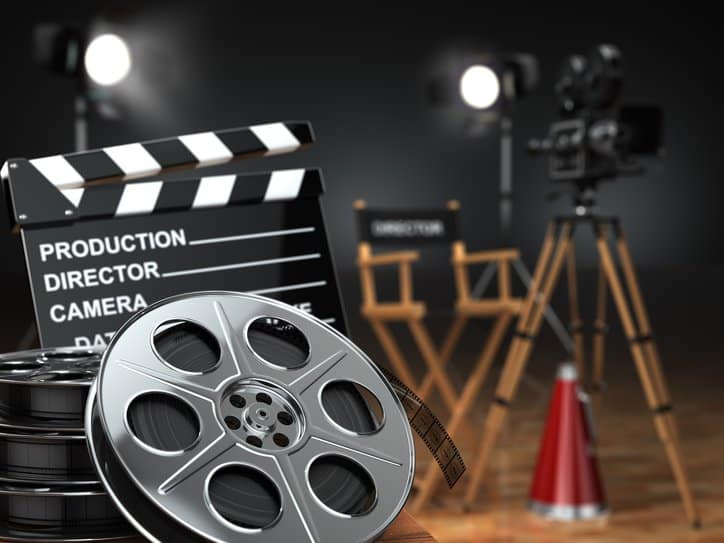 Retro camera, film reels (that adhere to ISO 4241:2019), clapperboard and director chair demonstrating cinema concept.