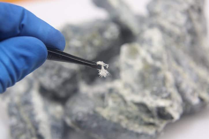A macro photograph fibers of the mineral chrysotile asbestos taken from the host rock with tweezers discovered from ISO 10312:2019 test method.