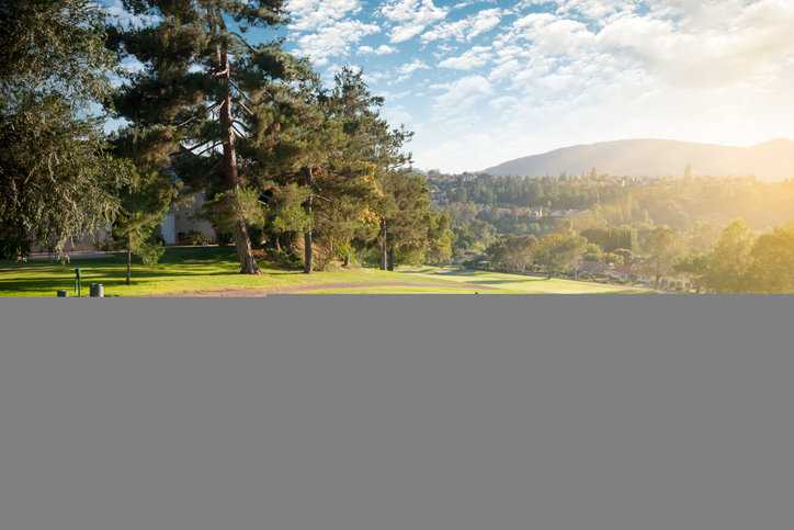 A man teeing off as his friends on a beautiful, sunny day at the golf course.