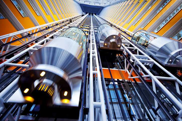 Elevators moving in colorful outside shaft and designed to ASME A17.1-2022.