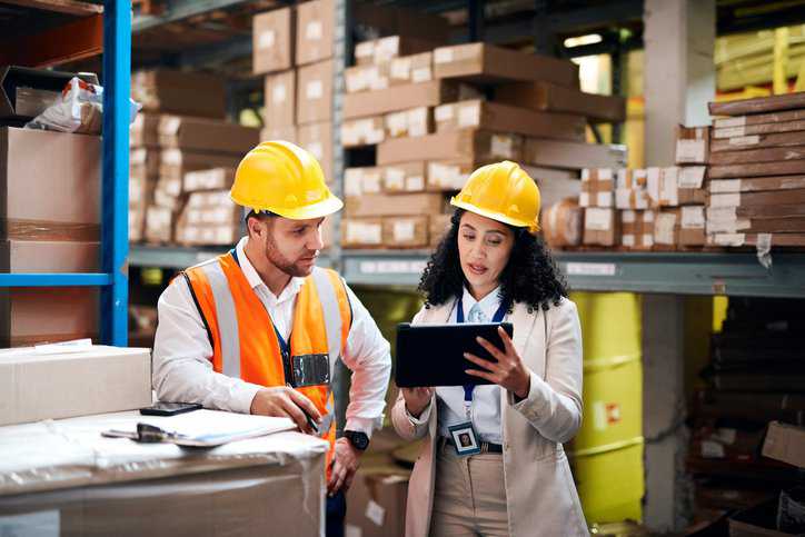 Factory industry partner and worker on digital technology implementing an ISO 28000 security management system for the supply chain.
