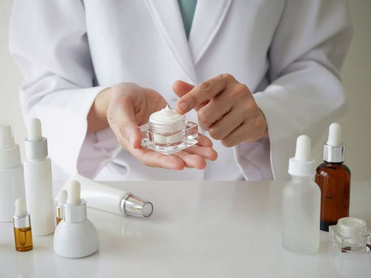 Woman putting on skin creams and lotions that adhere to ASTM E1490-19 to moisturize her skin.