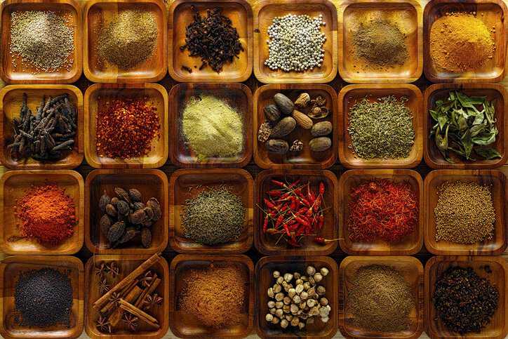 A large selection of cooking spices (chili ,cumin, tumeric, corriander, cumin, cardamon, garam masala, saffron, cinamon and star anise, poppy seed, sesame, cloves, nutmeg, black and white pepper corns, aniseed and fenugreek) in wooden trays adhering to ISO 939:2021.