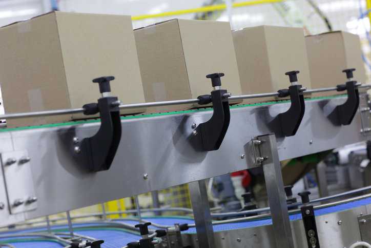 Cardboard boxes sliding along an ANSI/PMMI B155.1-2023 conveyor belt.