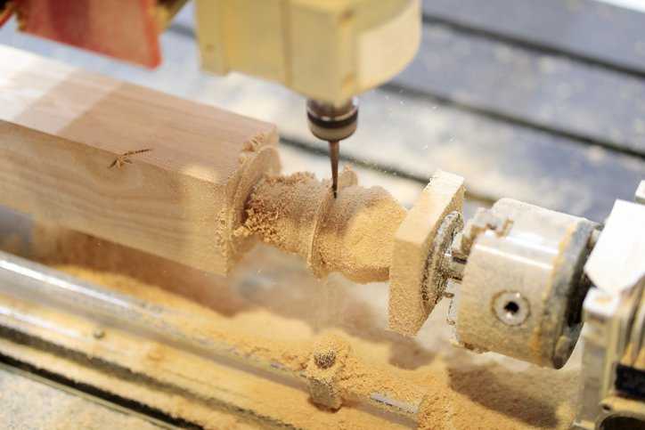 Workpiece processing on CNC wood turning lathe machine adhering to ANSI O1.1-2013 (R2023) woodworking machine specifications.