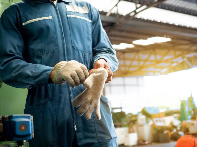 An engineer working in a manufacturing lab and is wearing hand protection adhering to ANSI/ISEA 105-2016.