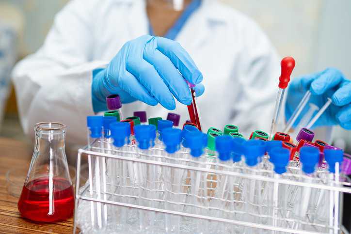 Scientist holding a micropipette with an anticoagulant adhering to color coding specifications in ASTM E1048-88(2021).